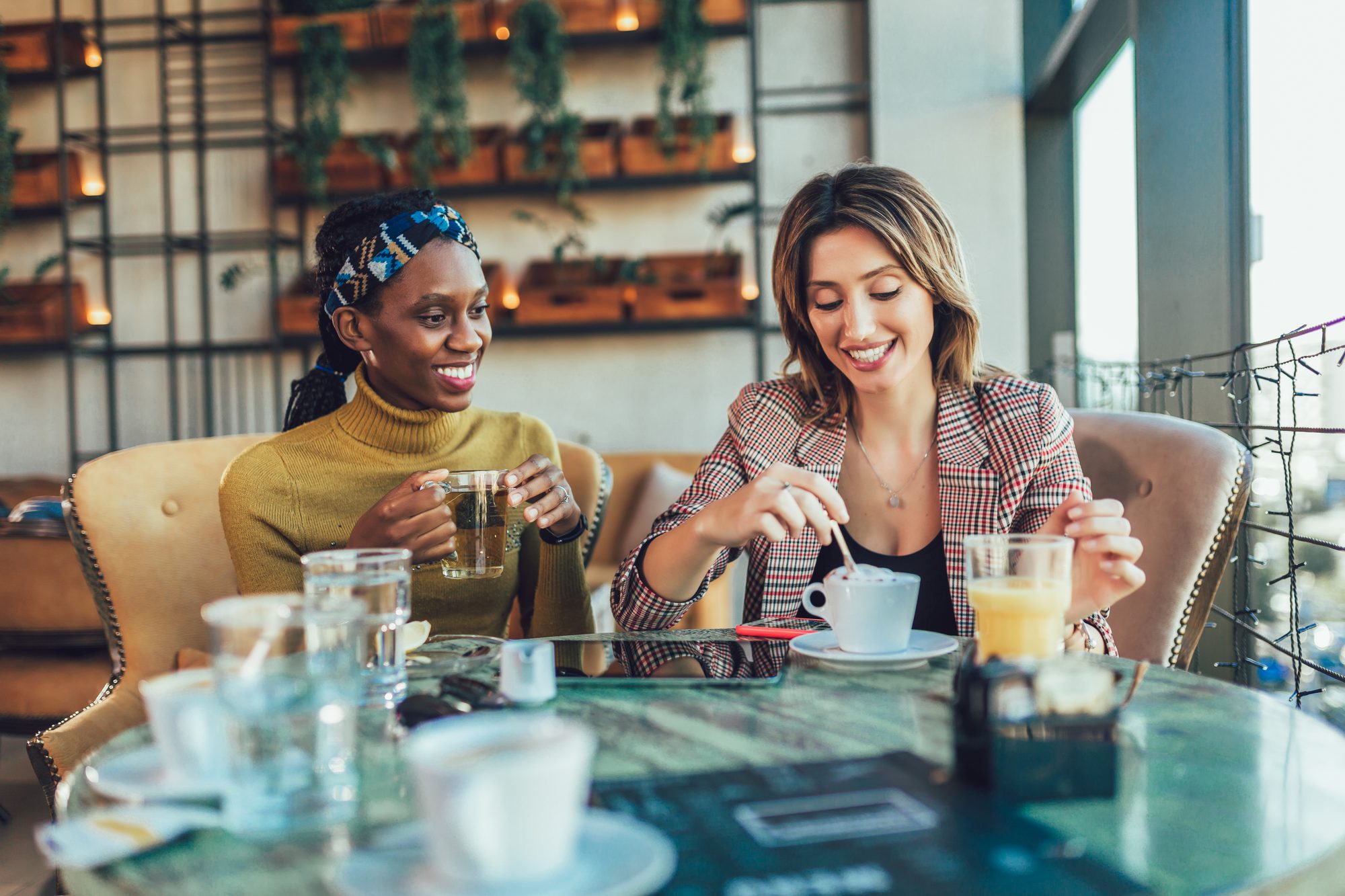 Two women smiling and chatting warmly together over coffee